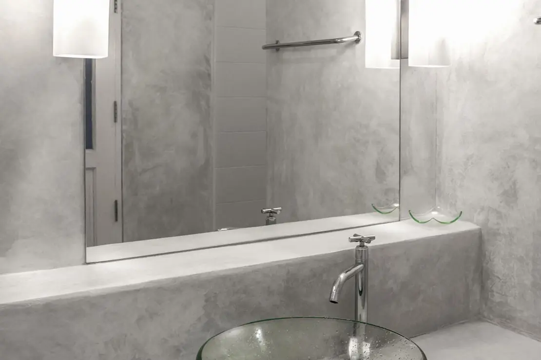 Baño con paredes y superficie de microcemento en tono gris.
